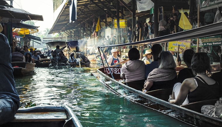 Visitors travelling by boat through a floating market