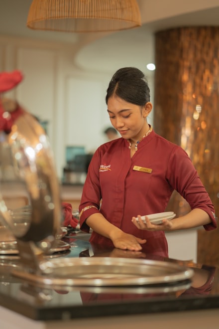 A restaurant server in uniform carrying plates