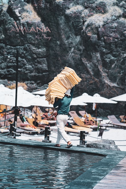 A resort attendant carrying folded towels past sun loungers